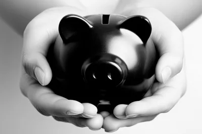 Hands Holding A Black Piggy Bank