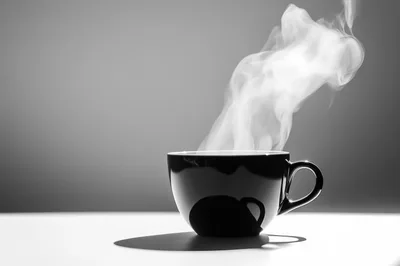 Steaming Black Coffee Cup On A White Surface
