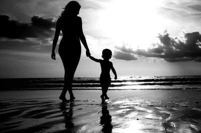 Mother And Child Walking Hand In Hand On Beach