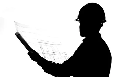 Silhouette Of A Construction Engineer Reviewing Blueprints