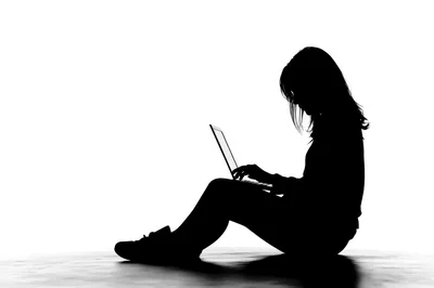 Silhouette Of A Woman Sitting And Using A Laptop
