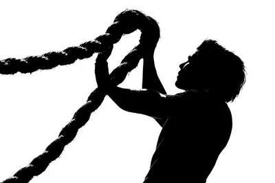 Silhouette of a Man Climbing a Thick Rope