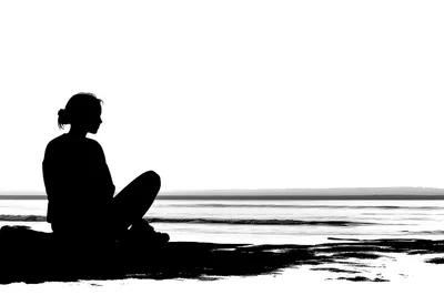 Silhouette Of A Woman Sitting By The Sea