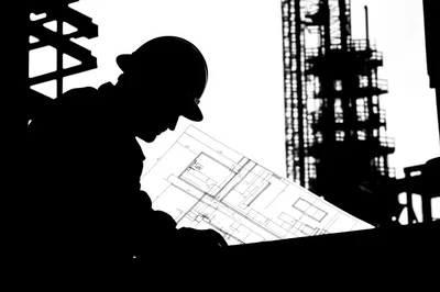 Silhouette of Engineer Reviewing Construction Blueprints