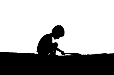 Silhouette Of A Child Playing In The Sand