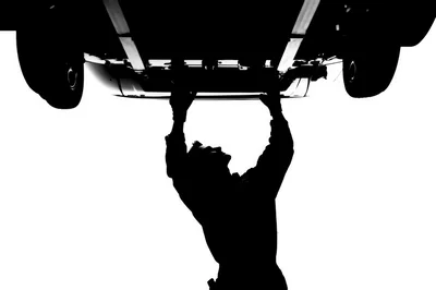 Silhouette Of A Mechanic Working Under A Car