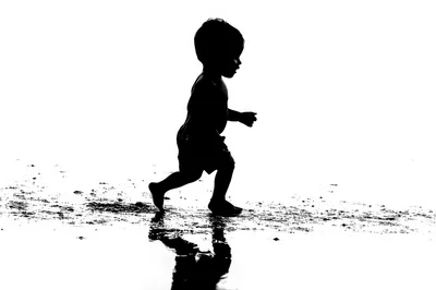 Silhouette Of A Toddler Running On The Beach