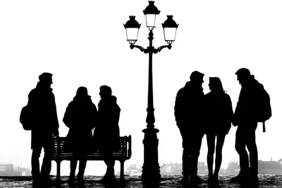 Silhouettes Of People Socializing By A Street Lamp
