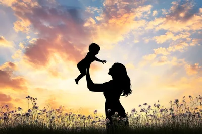 Silhouette of Mother Lifting Baby at Sunset