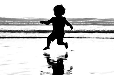 Silhouette of a Young Child Jumping on the Beach