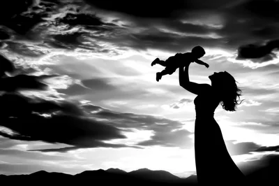 Silhouette Of A Mother Lifting Her Baby At Sunset