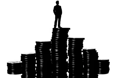 Silhouette Of A Businessman Standing On Coin Stacks