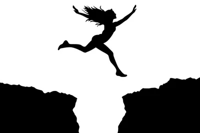 Silhouette Of A Woman Jumping Across A Mountain Gap