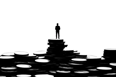 Silhouette Of A Businessman Standing On A Coin Stack