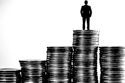 Silhouette Of Businessman Standing On Stack Of Coins