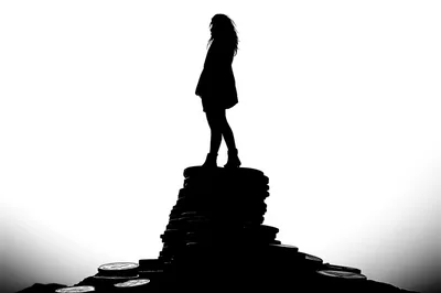 Silhouette Of A Woman Standing On A Stack Of Coins
