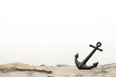 Black Metal Anchor Resting On A Rocky Shore