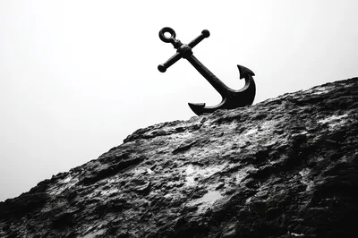 Black Metal Anchor Resting On A Rocky Cliffside