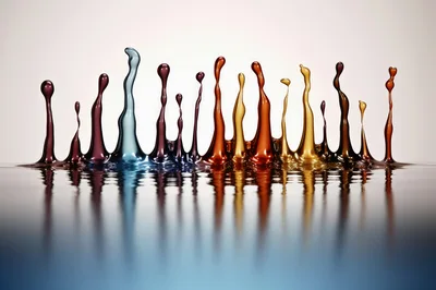 Colorful Liquid Splashes Rising From A Reflective Surface