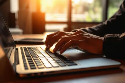 Person Typing On A Laptop In A Sunny Office