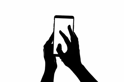 Silhouette Of Hands Interacting With A Smartphone Screen