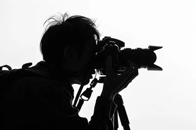 Silhouette Of A Photographer Using A Camera On Tripod