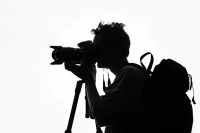 Silhouette Of A Photographer Using A Camera On Tripod