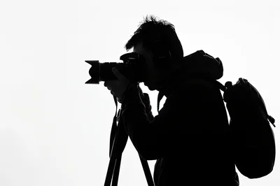 Silhouette Of A Photographer Using A Camera On Tripod