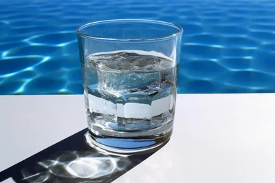 Glass Of Water With Ice Cubes By A Pool
