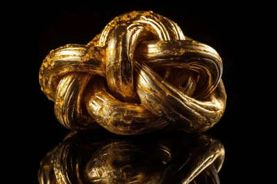 Golden Knot Sculpture On Reflective Black Surface