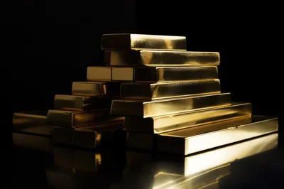 Stack Of Shiny Gold Bars On Reflective Surface
