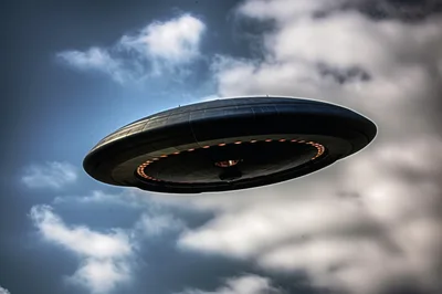 Metallic Flying Saucer Hovering In Cloudy Sky