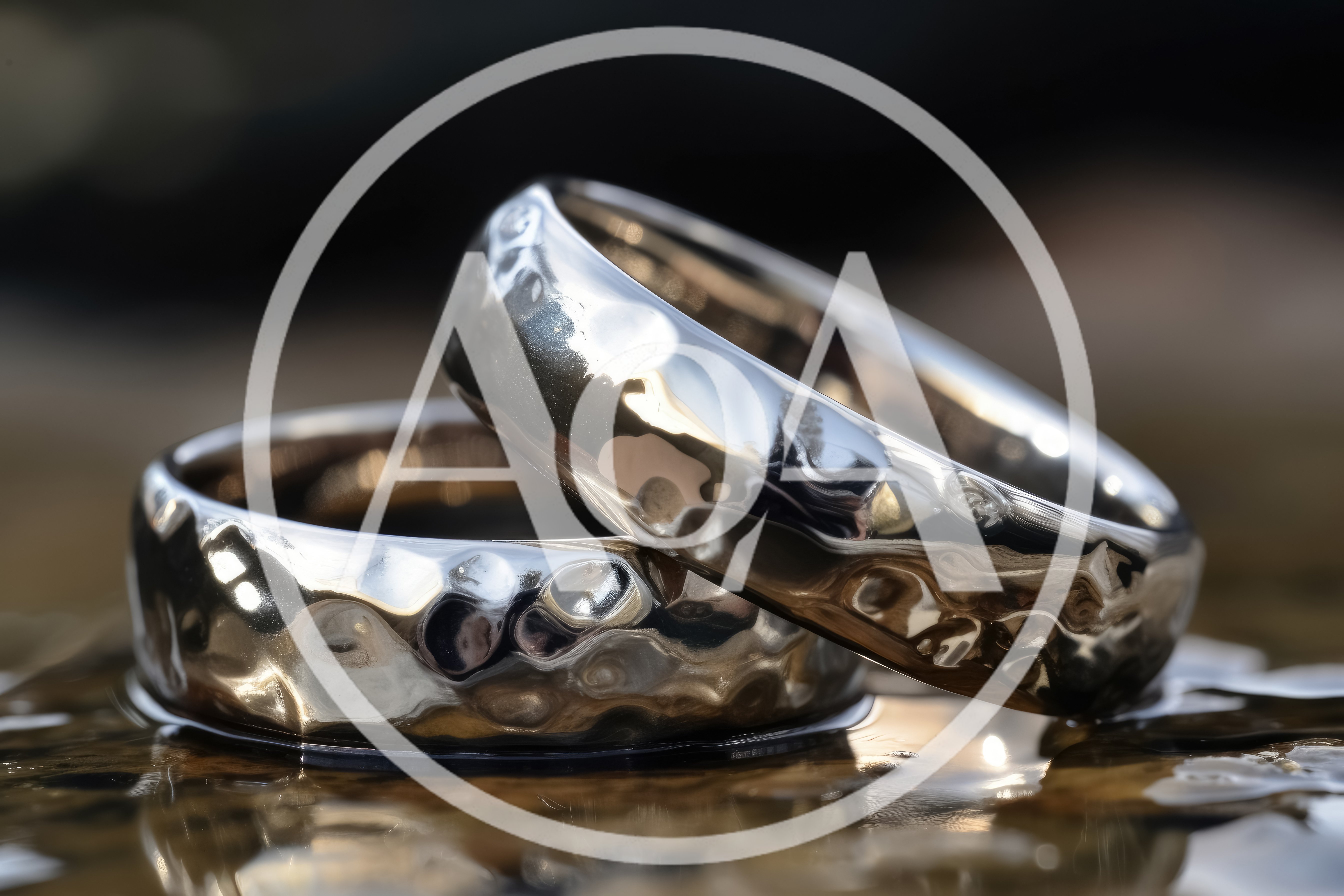 Two Hammered Silver Wedding Bands Resting On Wet Surface