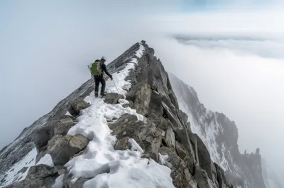 Mountaineer Traversing A Snowy Rocky Mountain Ridge