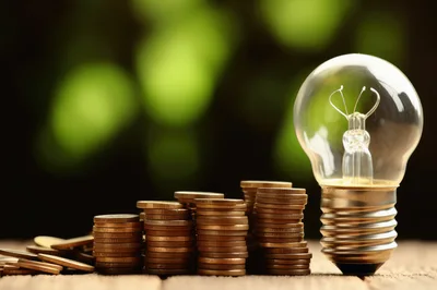 Light Bulb Beside Stacks of Gold Coins