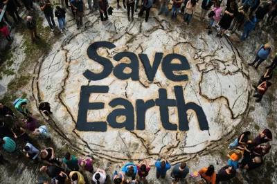 Group Of People Standing Around A Save Earth Mural