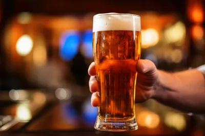 Hand Holding A Glass Of Cold Beer In A Bar