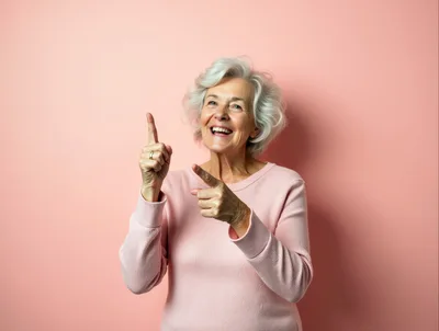 Cheerful Senior Woman Pointing Upwards Against Pink Background