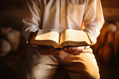 Person Holding An Open Bible In Warm Light