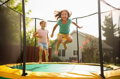 Two Happy Girls Jumping on a Backyard Trampoline