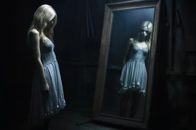 Young Woman Standing Before A Large Antique Mirror