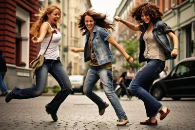 Three Young Women Jumping Joyfully on Cobblestone Street