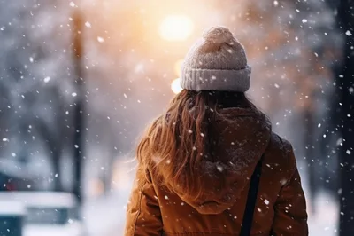 Woman Walking Through Snowy Park During Winter Sunset