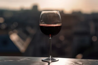 Glass Of Red Wine At Sunset Overlooking City