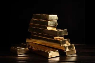 Stack of Shiny Gold Bars on Dark Wooden Surface
