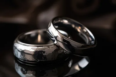 Two Polished Silver Wedding Rings On Reflective Surface