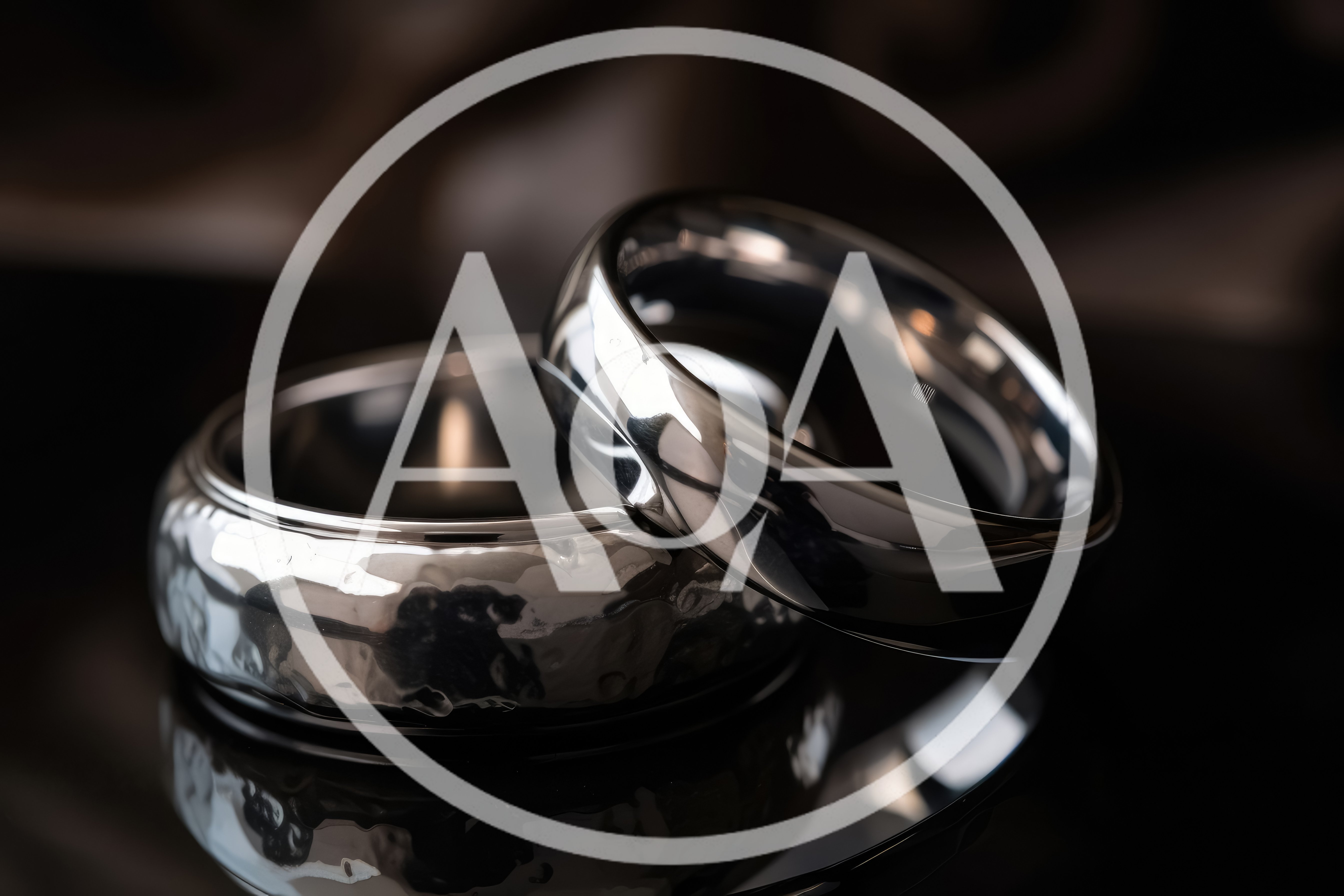 Two Polished Silver Wedding Rings On Reflective Surface