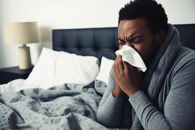 Sick Man Blowing Nose In Bed