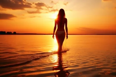 Silhouette Of A Woman Walking Into The Sunset Ocean