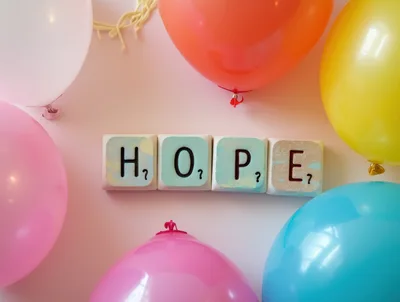 Wooden Blocks Spelling Hope Surrounded By Colorful Balloons